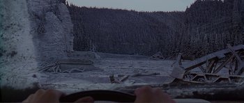 Movie still from “Dante's Peak” (1997), directed by Roger Donaldson – A person driving a car on a road near a forest; Extreme Wide shot, High angle