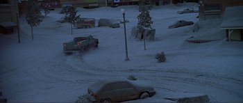 Movie still from “Dante's Peak” (1997), directed by Roger Donaldson – Cars are parked in the snow near a street light; Extreme Wide shot, High angle