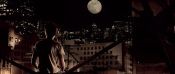 Movie still from “Daredevil” (2003), directed by Mark Steven Johnson – A man standing on a rooftop looking at a full moon; Wide shot, High angle