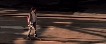 Movie still from “Daredevil” (2003), directed by Mark Steven Johnson – A woman riding a skateboard down the side of a road; Wide shot, Low angle