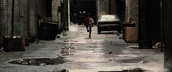 Movie still from “Daredevil” (2003), directed by Mark Steven Johnson – A person walking down a street with a backpack; Wide shot, High angle