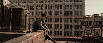 Movie still from “Daredevil” (2003), directed by Mark Steven Johnson – A man sitting on top of a brick wall; Wide shot, Low angle
