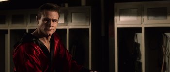 Movie still from “Daredevil” (2003), directed by Mark Steven Johnson – A man wearing a red robe in front of a row of lockers; Medium shot, Over the shoulder angle