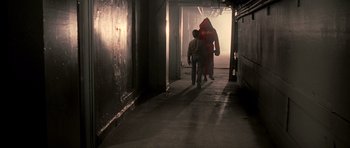 Movie still from “Daredevil” (2003), directed by Mark Steven Johnson – A man walking down a hallway with a fire hydrant; Wide shot, Over the shoulder angle