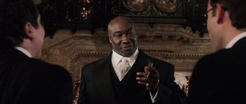 Movie still from “Daredevil” (2003), directed by Mark Steven Johnson – A man in a suit and tie holding a cell phone; Medium shot, Low angle