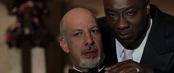Movie still from “Daredevil” (2003), directed by Mark Steven Johnson – A man with a bald head is getting his hair combed by another man; Close Up shot, Low angle