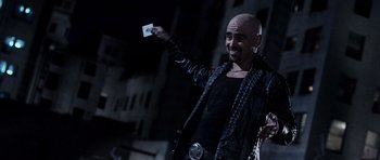 Movie still from “Daredevil” (2003), directed by Mark Steven Johnson – A man in a black jacket holding up a piece of paper; Medium shot, Over the shoulder angle