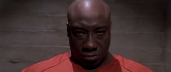 Movie still from “Daredevil” (2003), directed by Mark Steven Johnson – A man with a bald head wearing an orange t - shirt; Close Up shot, Low angle
