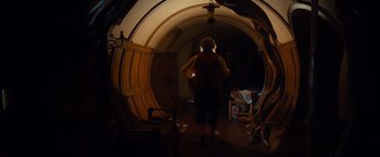 Movie still from “The Hobbit: An Unexpected Journey” (2012), directed by Peter Jackson – A woman standing inside of a room looking at her cell phone; Wide shot, Low angle