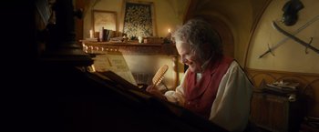 Movie still from “The Hobbit: An Unexpected Journey” (2012), directed by Peter Jackson – An older woman sitting in front of a piano holding a comb; Medium shot, Low angle