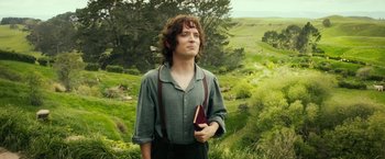 Movie still from “The Hobbit: An Unexpected Journey” (2012), directed by Peter Jackson – A man holding a book in his hands while standing in a field; Medium shot, Low angle