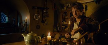 Movie still from “The Hobbit: An Unexpected Journey” (2012), directed by Peter Jackson – A man sitting in front of a table with candles; Medium shot, Over the shoulder angle