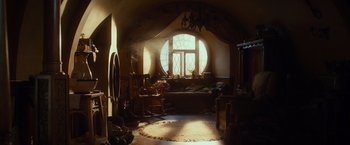 Movie still from “The Hobbit: An Unexpected Journey” (2012), directed by Peter Jackson – A living room with a couch and a chair in front of a large window; Wide shot, Low angle