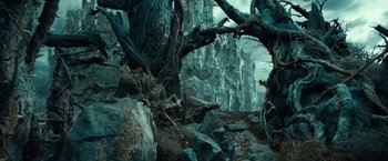 Movie still from “The Hobbit: An Unexpected Journey” (2012), directed by Peter Jackson – A forest scene with trees , rocks , and a mountain in the background; Wide shot, Low angle