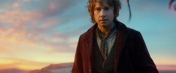 Movie still from “The Hobbit: An Unexpected Journey” (2012), directed by Peter Jackson – A man in a red jacket standing in front of a sunset; Close Up shot, Over the shoulder angle