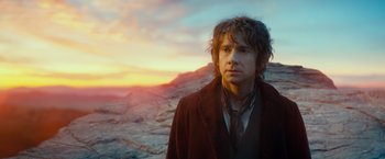 Movie still from “The Hobbit: An Unexpected Journey” (2012), directed by Peter Jackson – A man standing in front of a mountain range at sunset; Close Up shot, Over the shoulder angle