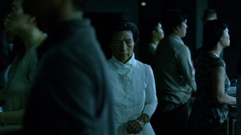Movie still from “Daredevil” (2015), created by Drew Goddard – An older asian woman in a white dress; Medium shot, Over the shoulder angle