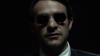 Movie still from “Daredevil” (2015), created by Drew Goddard – A person wearing a suit and sunglasses; Close Up shot, Low angle