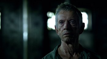 Movie still from “Daredevil” (2015), created by Drew Goddard – An old man with a gray beard looking at the camera; Close Up shot, Over the shoulder angle