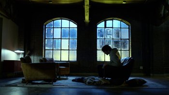 Movie still from “Daredevil” (2015), created by Drew Goddard – A man sitting in a chair next to a dog; Wide shot, High angle