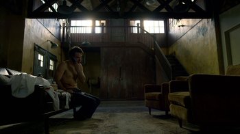 Movie still from “Daredevil” (2015), created by Drew Goddard – A man sitting on a chair talking on a phone; Wide shot, Low angle