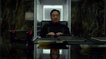 Movie still from “Daredevil” (2015), created by Drew Goddard – A man sitting at a table in front of a computer; Medium shot, Low angle