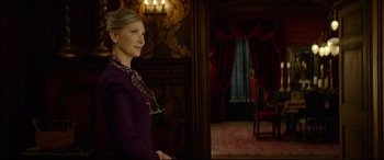 Movie still from “The House with a Clock in Its Walls” (2018), directed by Eli Roth – A woman in a purple dress standing in front of a window; Medium shot, Over the shoulder angle