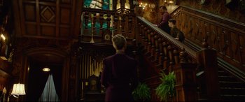 Movie still from “The House with a Clock in Its Walls” (2018), directed by Eli Roth – A woman standing on the bottom of a wooden staircase; Wide shot, Low angle
