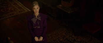 Movie still from “The House with a Clock in Its Walls” (2018), directed by Eli Roth – A woman in a purple dress standing in front of a rug; Medium shot, Low angle