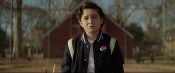 Movie still from “The House with a Clock in Its Walls” (2018), directed by Eli Roth – A young boy wearing a baseball jacket in front of a barn; Medium shot, Over the shoulder angle