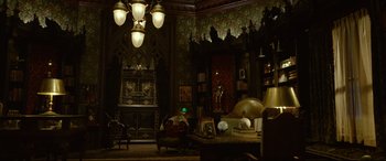 Movie still from “The House with a Clock in Its Walls” (2018), directed by Eli Roth – A living room filled with furniture next to a fireplace; Extreme Wide shot, High angle