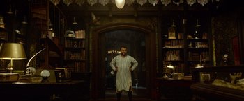 Movie still from “The House with a Clock in Its Walls” (2018), directed by Eli Roth – A man standing in front of an archway in a room; Wide shot, Low angle