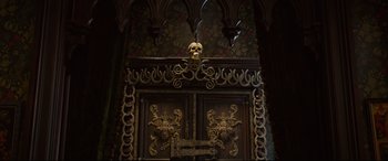 Movie still from “The House with a Clock in Its Walls” (2018), directed by Eli Roth – A skull on top of an ornate wooden door; Wide shot, Low angle
