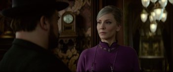 Movie still from “The House with a Clock in Its Walls” (2018), directed by Eli Roth – A woman wearing a purple sweater standing in front of a clock; Close Up shot, Over the shoulder angle