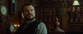Movie still from “The House with a Clock in Its Walls” (2018), directed by Eli Roth – A man with a goatee standing in front of a wooden statue; Close Up shot, Low angle