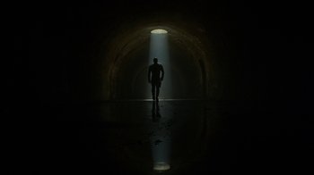 Movie still from “Daredevil” (2015), created by Drew Goddard – A man standing in a dark tunnel with light coming from the window; Extreme Wide shot, Low angle