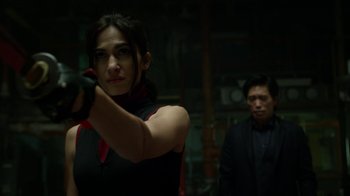 Movie still from “Daredevil” (2015), created by Drew Goddard – A woman holding a gun while standing next to a man; Close Up shot, Over the shoulder angle