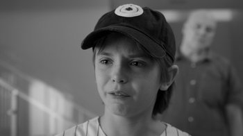 Movie still from “Daredevil” (2015), created by Drew Goddard – A young girl wearing a baseball cap and a baseball uniform; Close Up shot, Over the shoulder angle