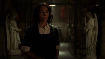 Movie still from “Daredevil” (2015), created by Drew Goddard – A woman standing in a dark room in front of a painting; Medium shot, Low angle