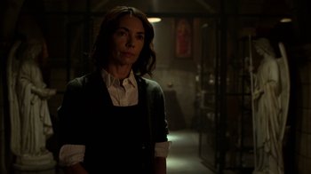 Movie still from “Daredevil” (2015), created by Drew Goddard – A woman standing in a dark room in front of a painting; Medium shot, Over the shoulder angle