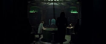 Movie still from “Dark City” (1998), directed by Alex Proyas – Two people in a dark room with a green light; Wide shot, High angle