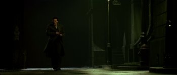 Movie still from “Dark City” (1998), directed by Alex Proyas – A man standing on the sidewalk in the dark; Wide shot, Low angle