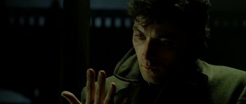 Movie still from “Dark City” (1998), directed by Alex Proyas – A man in a hooded jacket looking at the camera; Close Up shot, Over the shoulder angle