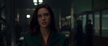 Movie still from “Dark City” (1998), directed by Alex Proyas – A woman in a green jacket standing in a dark room; Close Up shot, Over the shoulder angle