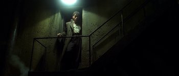 Movie still from “Dark City” (1998), directed by Alex Proyas – A man standing on the stairs of a building; Wide shot, Low angle