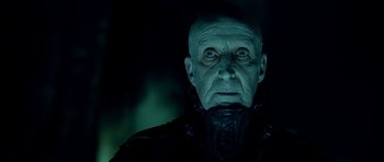 Movie still from “Dark City” (1998), directed by Alex Proyas – An old man in a black jacket is looking at the camera; Close Up shot, Low angle