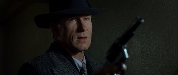 Movie still from “Dark City” (1998), directed by Alex Proyas – A person wearing a suit and hat; Close Up shot, Low angle