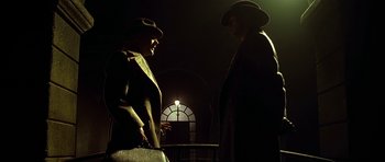 Movie still from “Dark City” (1998), directed by Alex Proyas – Two men standing next to each other near a candle; Medium shot, Low angle