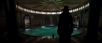 Movie still from “Dark City” (1998), directed by Alex Proyas – A man standing in front of an indoor swimming pool; Wide shot, Low angle