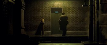Movie still from “Dark City” (1998), directed by Alex Proyas – A man standing in front of a brick wall; Wide shot, Low angle